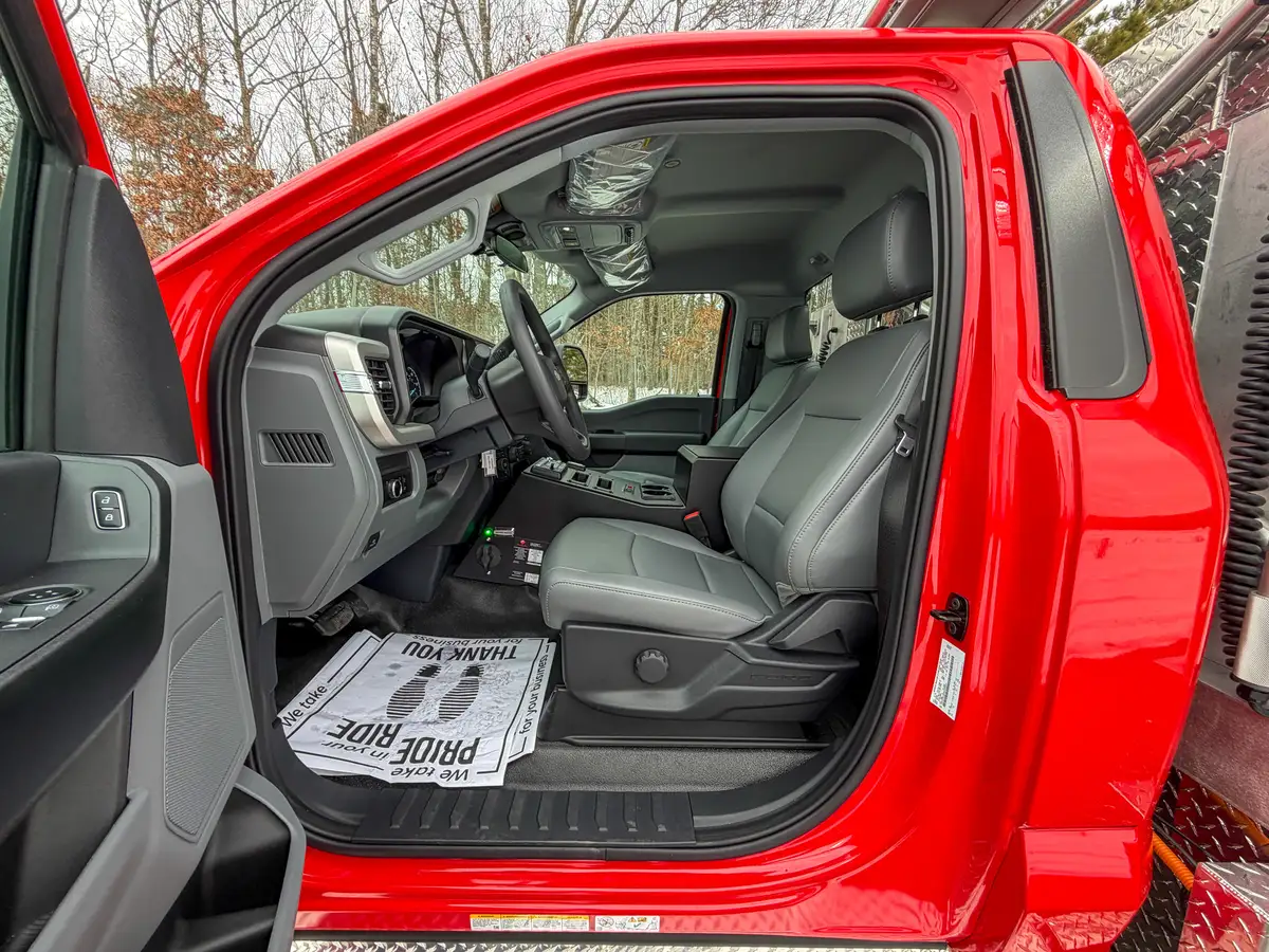 Driver seat and dashboard view through open door.